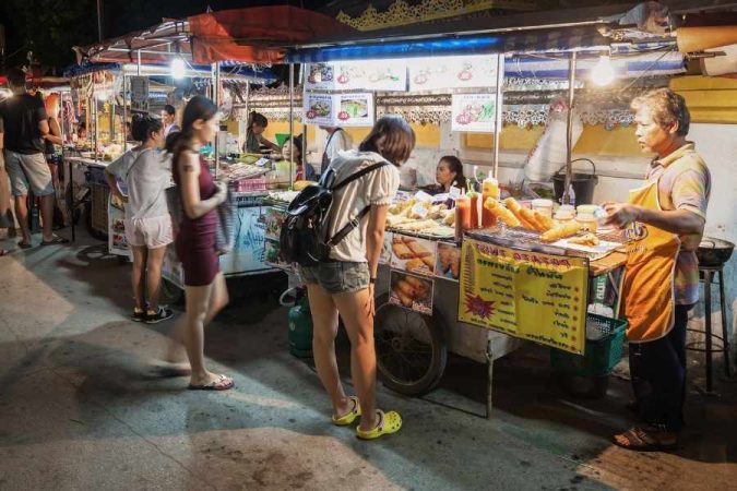 Des clients choisissent des plats sur les marchés locaux lors d'une soirée animée.