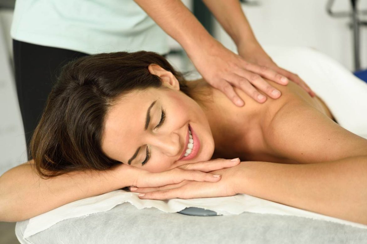 Une femme souriante et détendue recevant un soin du dos en cabinet pour illustrer le lien entre massage et santé mentale.